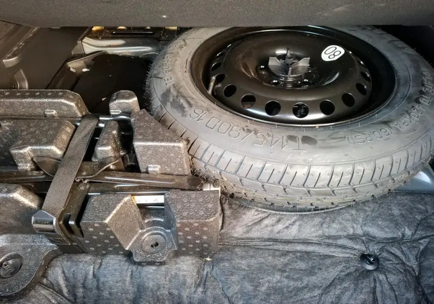 Vue rapprochée de la roue de secours galette noire dans le coffre du Renault Arkana 2023 hybride noir métal.