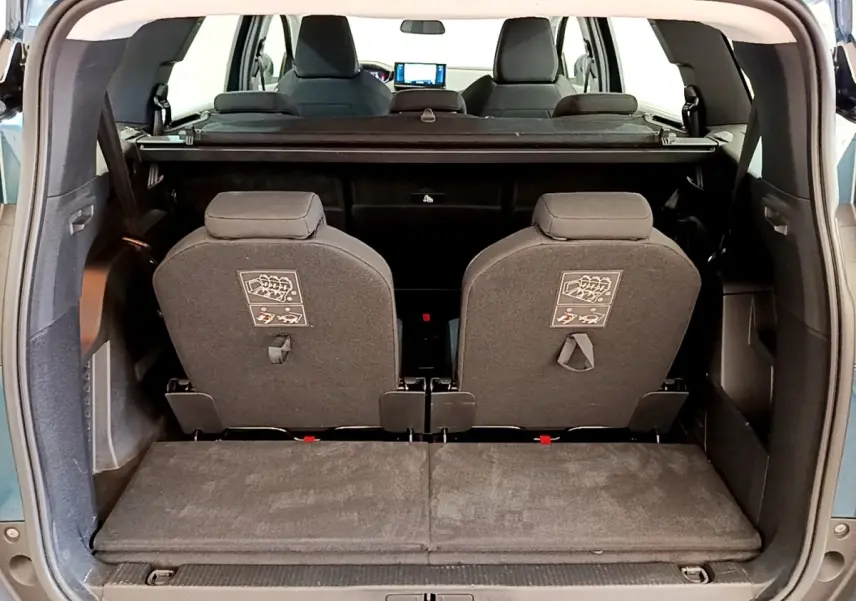 Vue arrière du coffre ouvert du Peugeot 5008 bleu, montrant la troisième rangée de sièges individuels relevés.