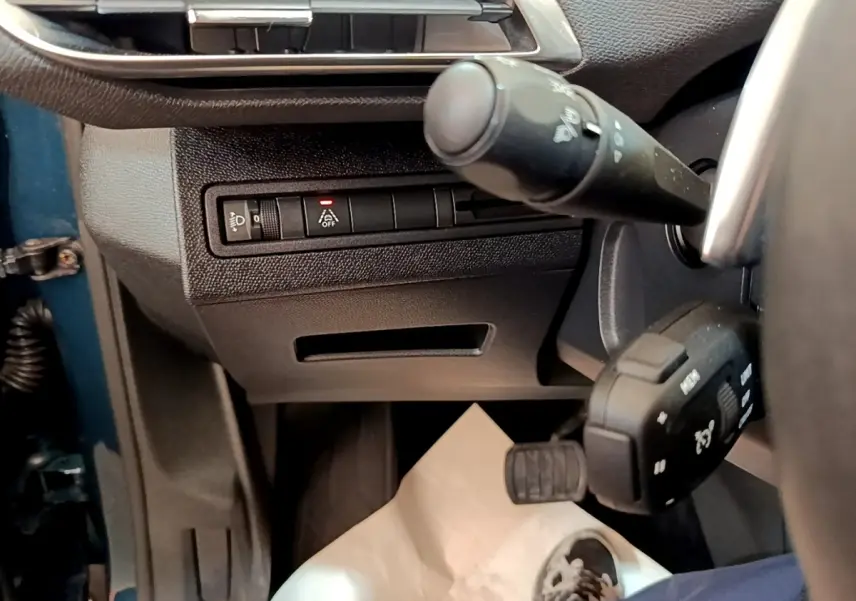 Détail intérieur côté gauche du tableau de bord Peugeot 5008 bleu, avec commandes d’éclairage et volant partiel visible.