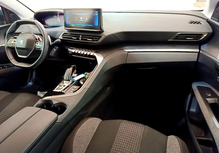 Intérieur du Peugeot 5008 bleu, vue côté conducteur, tableau de bord moderne avec écran tactile central et volant cuir multifonctions.