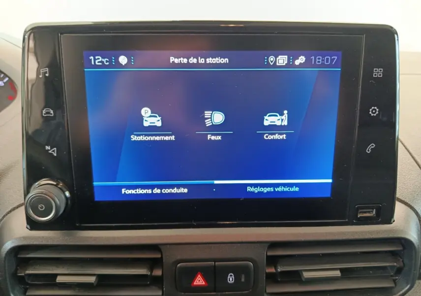 Écran tactile central du Peugeot Partner blanc 2021 affichant les réglages de stationnement, feux et confort.