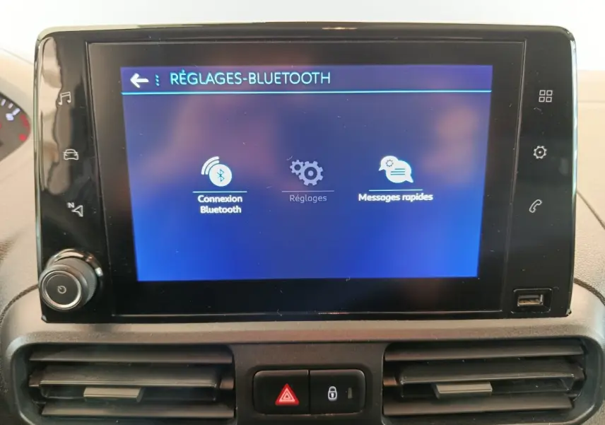 Vue rapprochée de l'écran tactile central du Peugeot Partner blanc 2021 affichant le menu réglages Bluetooth.