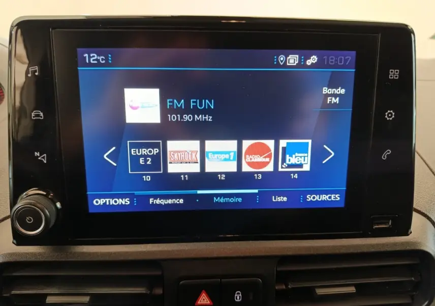 Écran tactile central du Peugeot Partner blanc 2021 affichant les stations radio FM avec commandes autour.