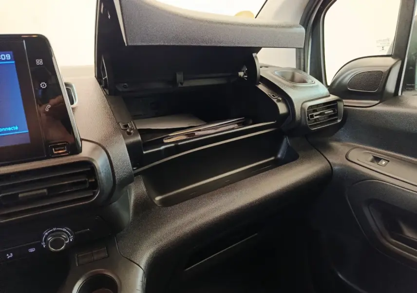 Intérieur du Peugeot Partner 2021, vue côté passager sur la boîte à gants ouverte et la console noire.