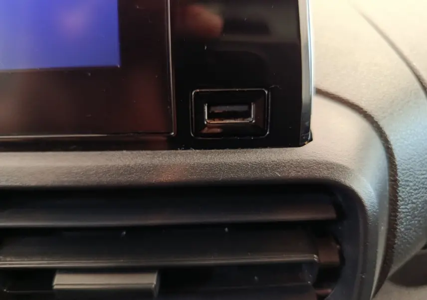 Gros plan sur la prise USB noire intégrée à la console centrale du Peugeot Partner 2021, intérieur gris.