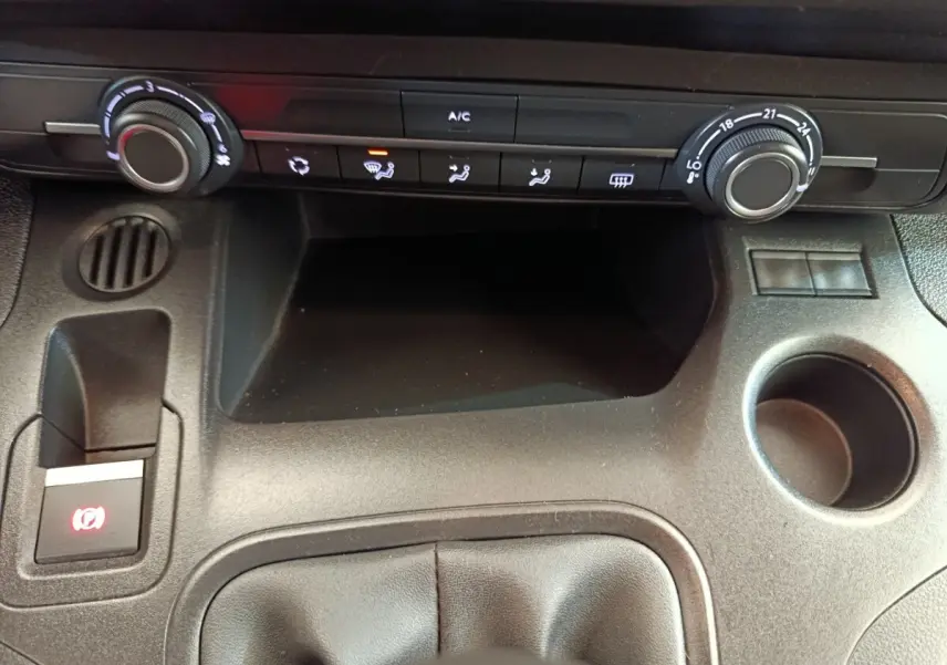 Vue rapprochée de la console centrale noire du Peugeot Partner 2021, avec commandes climatisation et frein à main électrique.