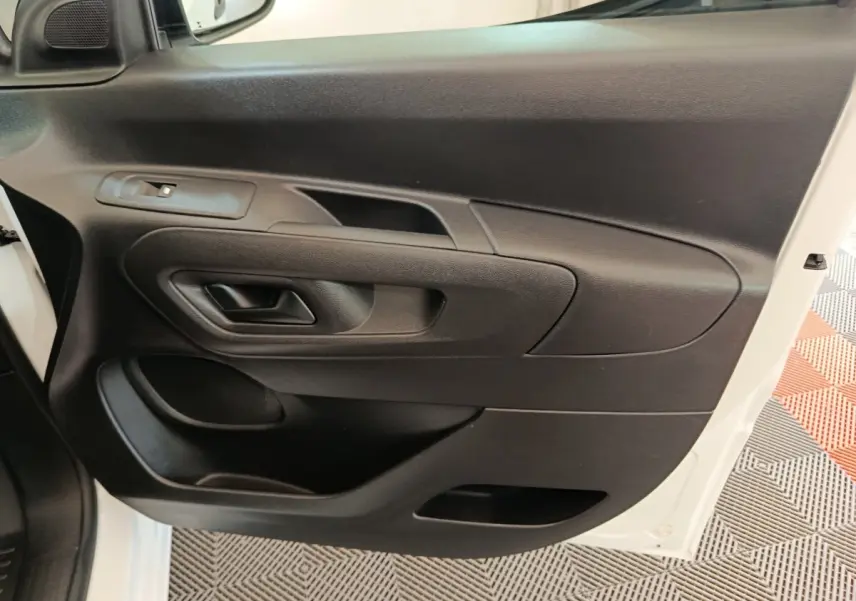 Vue rapprochée de la porte avant gauche noire intérieure du Peugeot Partner blanc, avec poignée et commande de vitre.