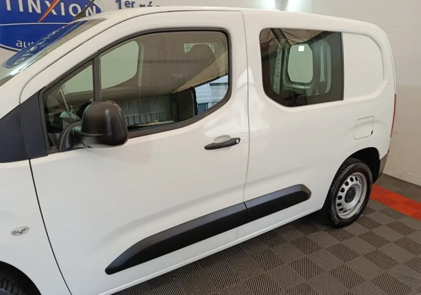Vue de profil côté gauche d'un Peugeot Partner blanc 2021 avec porte latérale coulissante et jantes acier.