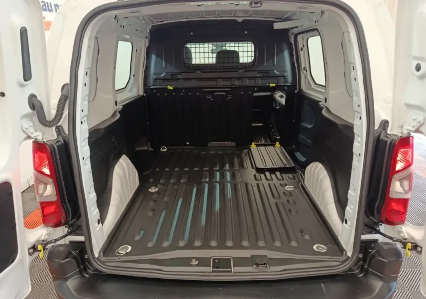 Vue arrière du coffre blanc du Peugeot Partner 2021, montrant l'espace de chargement vide avec cloison pleine noire.