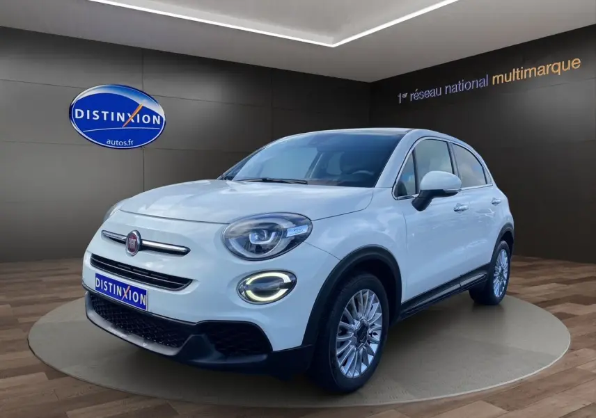 Vue 3/4 avant d'une FIAT 500X blanche avec jantes alliage et éclairage LED circulaire allumé.