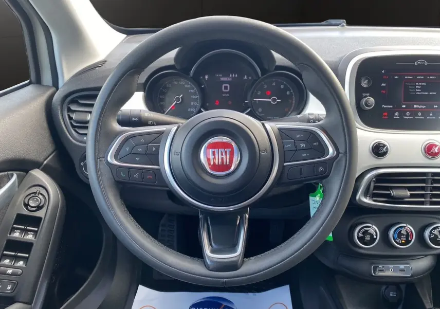 Vue intérieure centrée sur le volant noir de la FIAT 500X 2018 avec tableau de bord et commandes visibles.