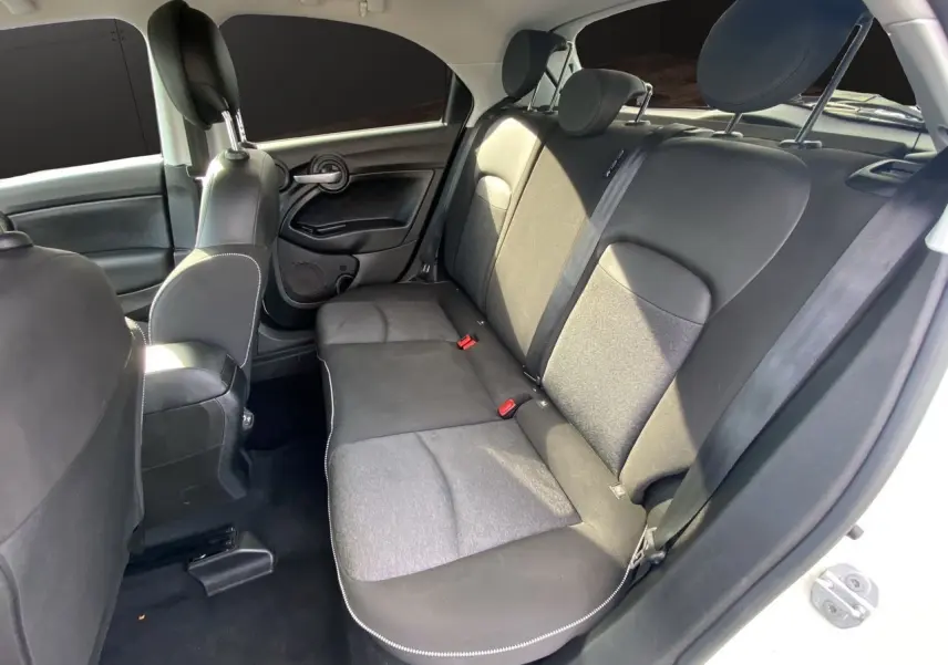 Vue intérieure arrière côté droit d'une Fiat 500X blanche, sièges noirs en tissu et cuir avec appuie-têtes réglables.