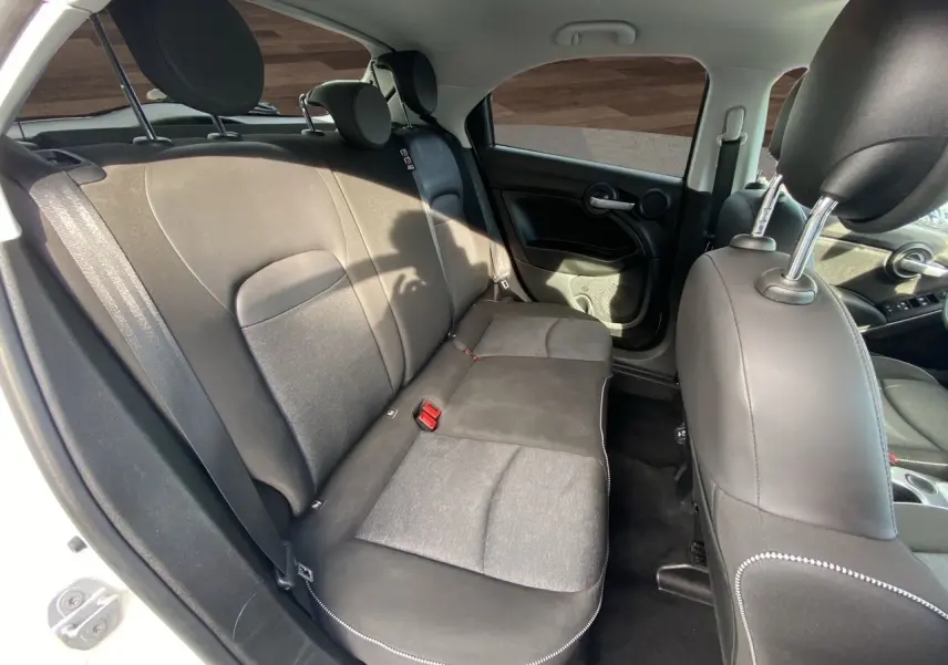 Vue intérieure arrière du Fiat 500X blanc de 2018, montrant les sièges arrière en tissu noir avec surpiqûres blanches.