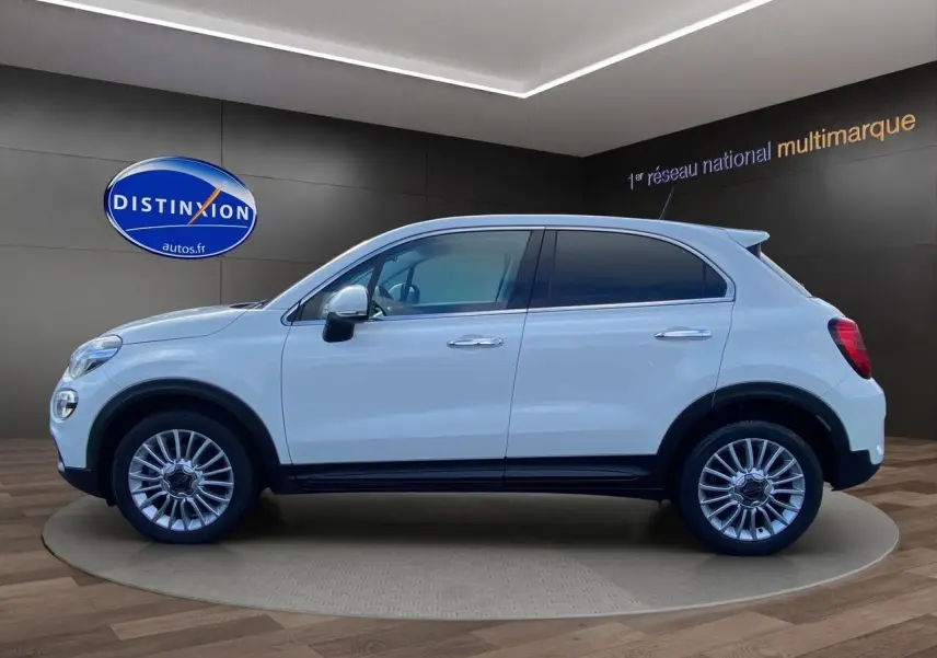 Profil côté gauche d'un FIAT 500X blanc 5 portes, avec jantes alliage et vitres teintées, en showroom.