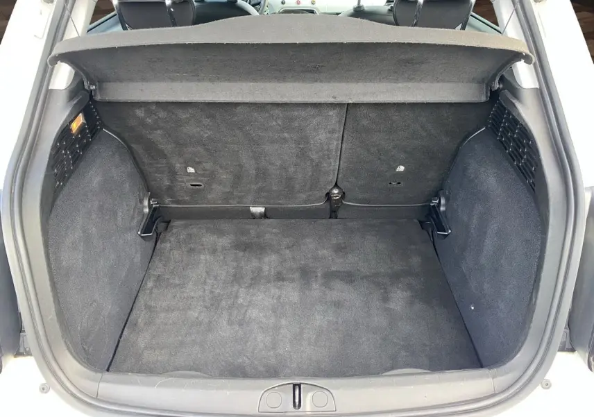 Vue arrière du coffre noir spacieux de la FIAT 500X blanche, avec banquette arrière et cache-bagages visibles.