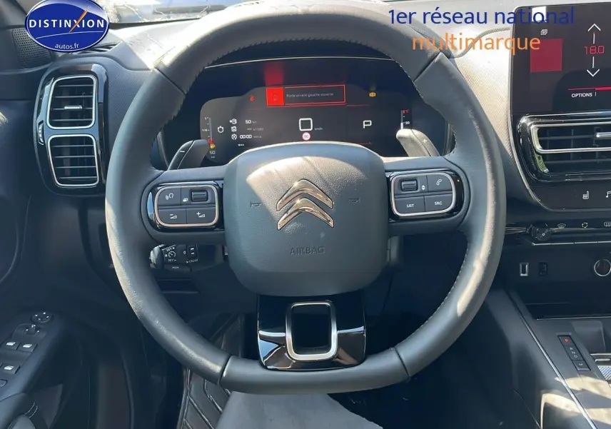 Vue intérieure centrée sur le volant noir du Citroën C5 Aircross 2025 avec tableau de bord digital et écran tactile.