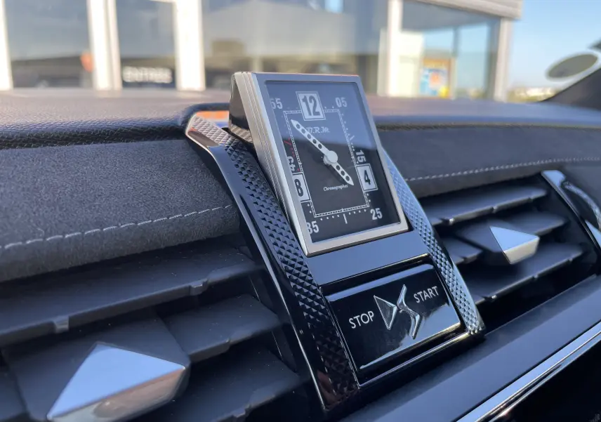 Gros plan sur l'horloge analogique et les commandes stop/start sur le tableau de bord noir du DS7 gris Artens.
