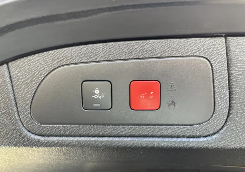Gros plan sur les boutons de commande de coffre, noir et rouge, dans l'habitacle d'un DS7 gris Artens 2018.