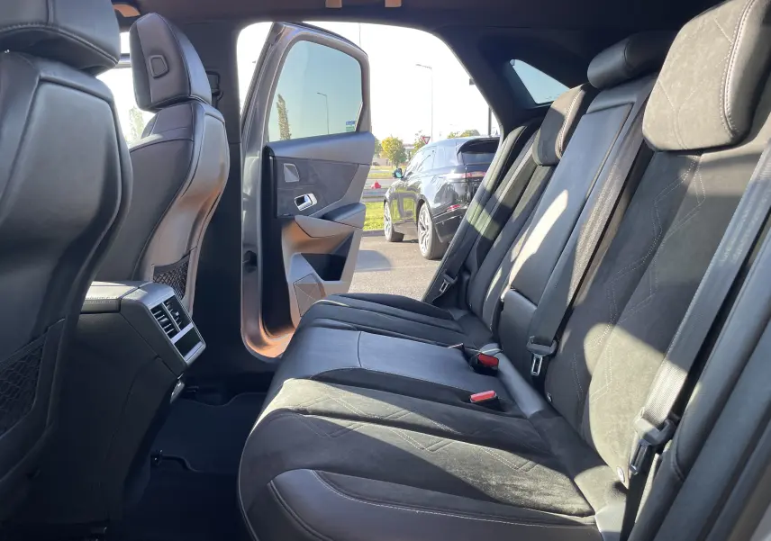 Vue intérieure côté droit des sièges arrière en cuir noir du DS7 gris, porte arrière ouverte laissant entrer la lumière naturelle.