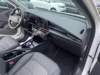 Intérieur du Kia Niro EV 204 CV Active 2024 blanc, vue côté passager montrant tableau de bord et sièges gris.