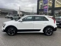 Vue de profil côté gauche d'un KIA Niro EV blanc 204 CV Active 2024, avec jantes noires et détails noirs sur les bas de caisse.
