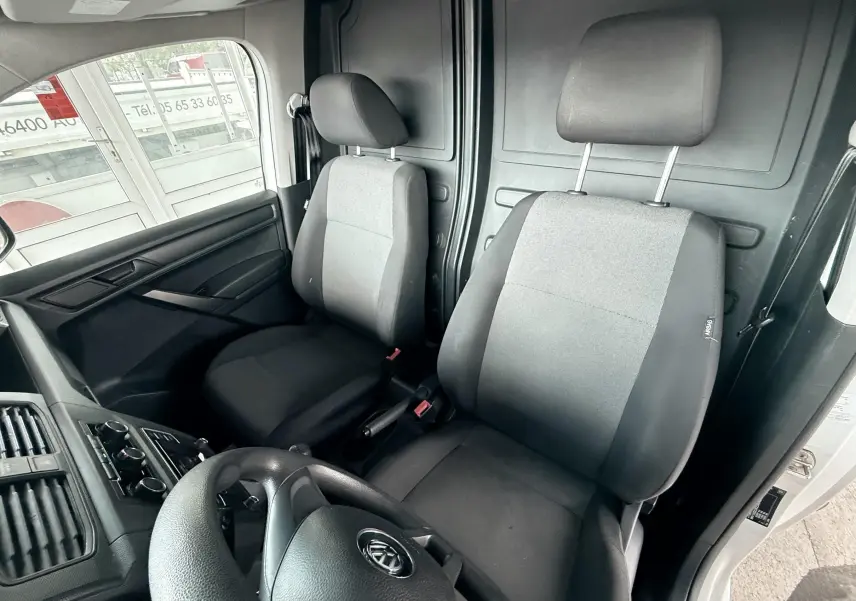 Vue intérieure avant du Volkswagen Caddy Maxi Long 2017, sièges tissu noir et gris, volant visible côté gauche.