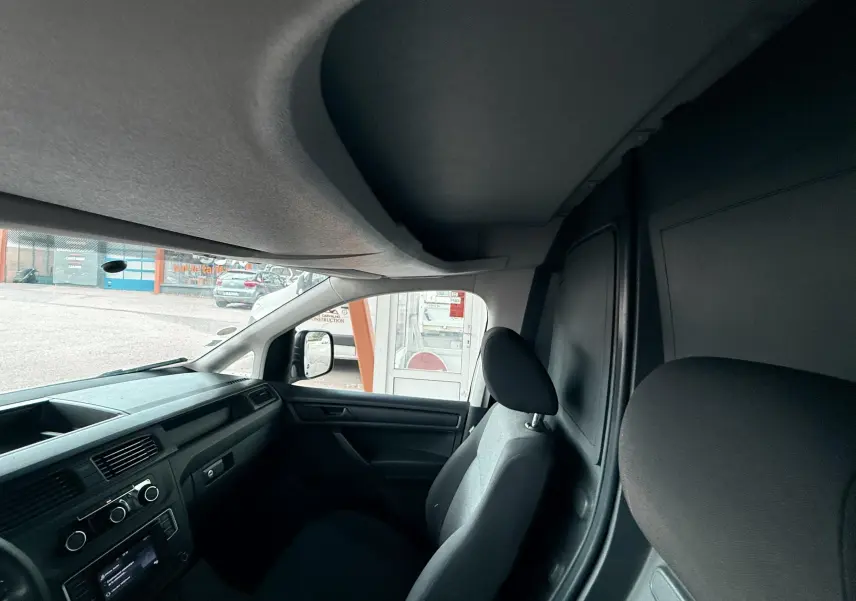 Vue intérieure côté passager du Volkswagen Caddy Maxi Long blanc, montrant les sièges et le tableau de bord noir.