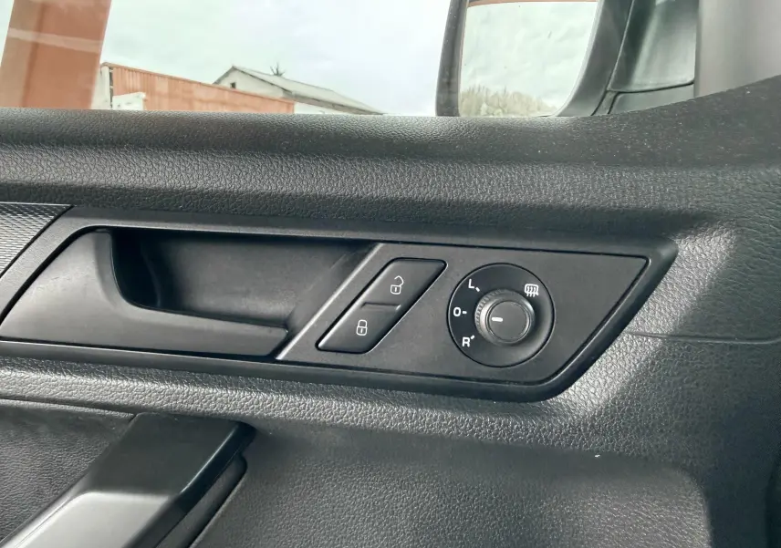 Détail de la porte côté conducteur du Volkswagen Caddy blanc 2017, avec commandes de verrouillage et réglage des rétroviseurs.