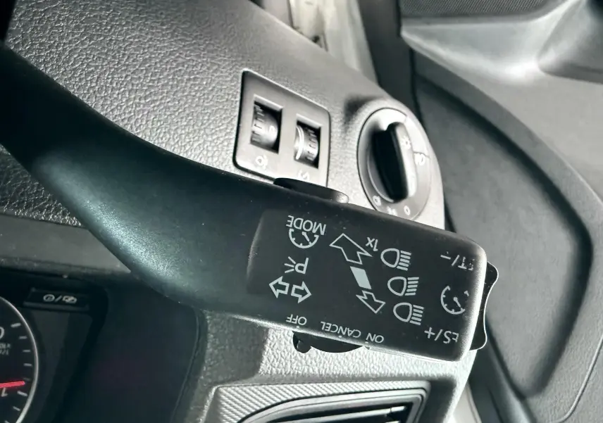 Gros plan sur la commande de clignotant et feux du Volkswagen Caddy blanc, vue intérieure côté gauche.