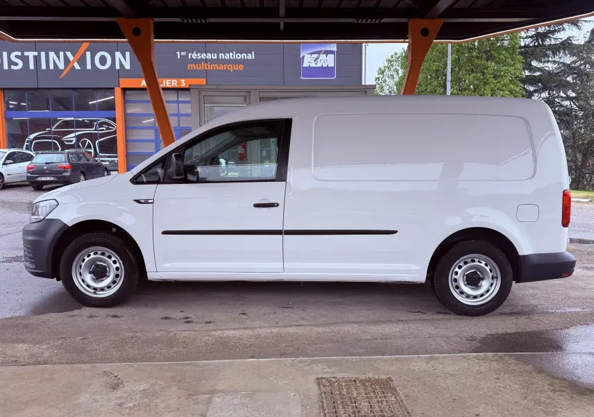 Vue de profil côté gauche d’un Volkswagen Caddy Maxi Long blanc, utilitaire avec jantes acier sous abri.