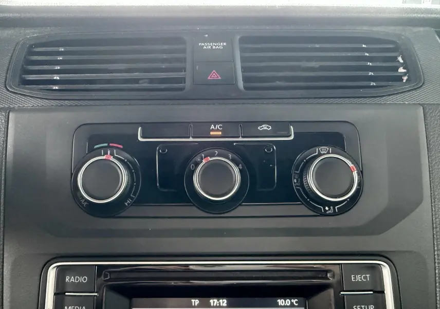 Gros plan sur la console centrale noire du Volkswagen Caddy, montrant les commandes de climatisation et l’écran radio.