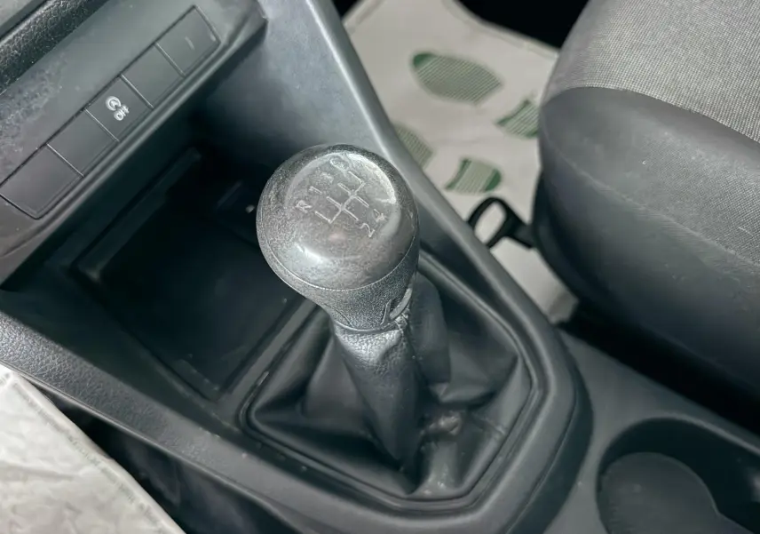 Gros plan sur le levier de vitesses manuel noir du Volkswagen Caddy Maxi Long 2017, siège tissu gris visible.