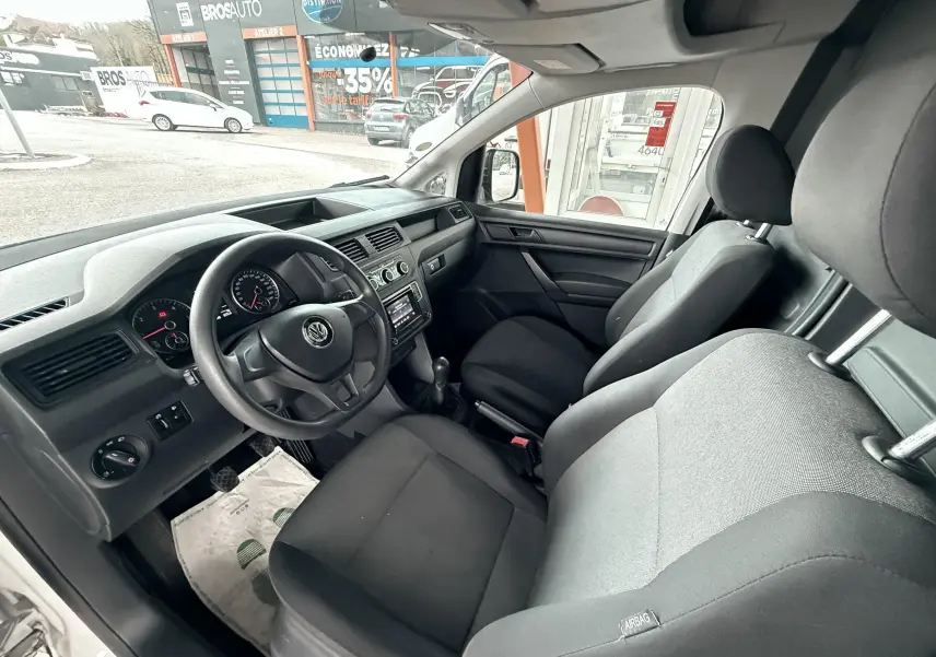 Vue intérieure côté conducteur du Volkswagen Caddy Maxi Long 2017, sièges tissu noir et tableau de bord gris foncé.