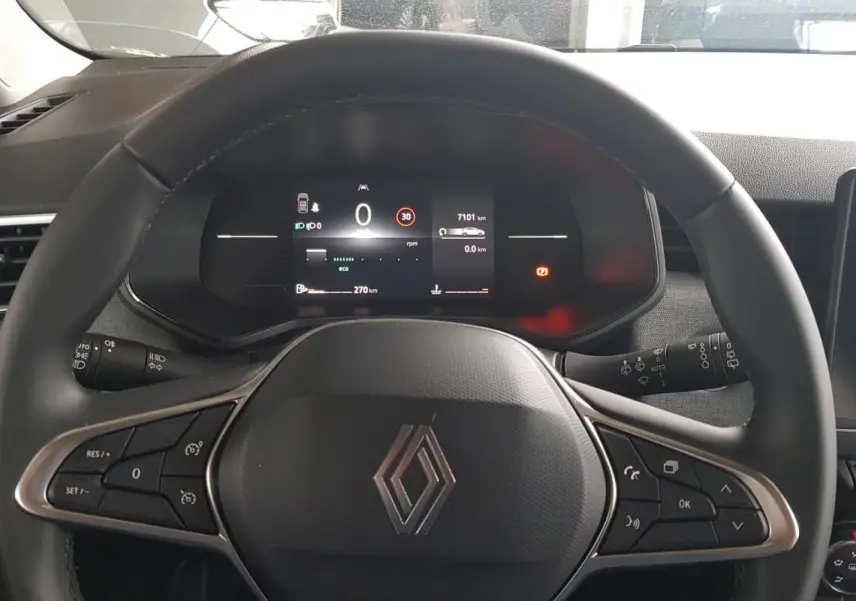 Vue intérieure centrée sur le volant noir de la Renault Clio 2025 avec tableau de bord numérique et écran tactile.