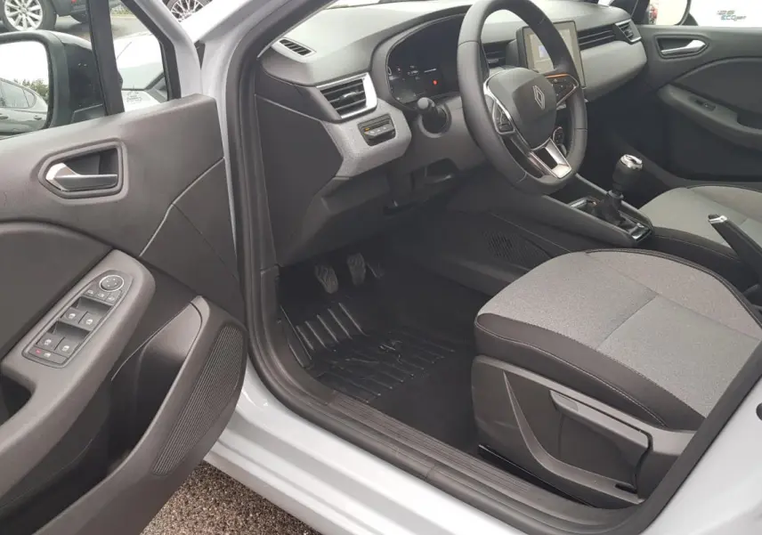 Vue intérieure côté conducteur de la Renault Clio gris 2025, montrant le tableau de bord et la boîte manuelle.