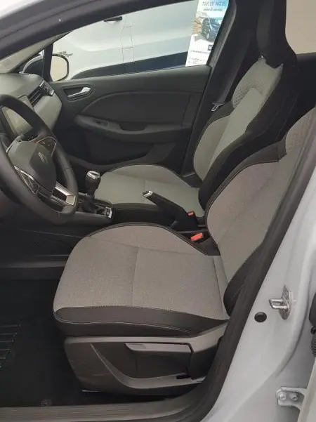 Vue intérieure côté conducteur de la Renault Clio gris 2025, montrant les sièges tissu et la boîte manuelle.