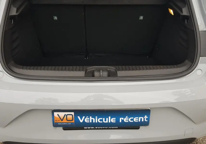 Coffre ouvert vu de l'arrière d'une Renault Clio gris clair 2025 avec feux arrière et pare-chocs visibles.