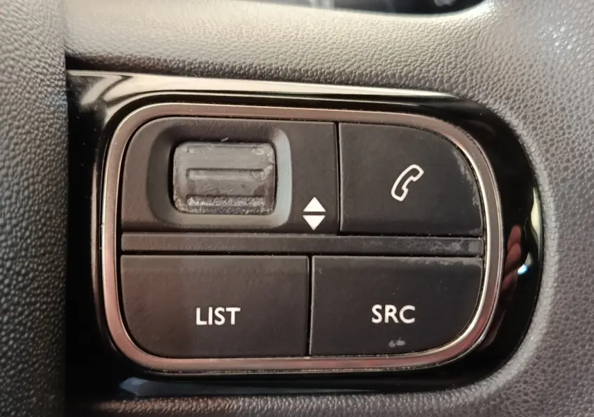 Gros plan sur les commandes noires du volant multifonctions de la Citroën C3 blanche de 2022.