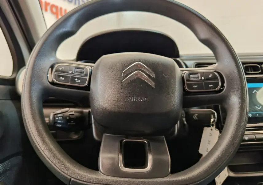 Vue rapprochée du volant multifonctions noir de la Citroën C3 2022 avec commandes intégrées et logo chrome central.