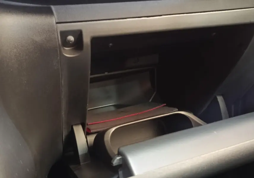 Gros plan sur la boîte à gants ouverte de la Citroën C3 blanche, montrant un rangement intérieur avec un livret.