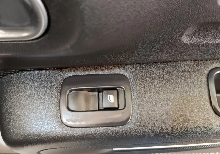 Gros plan sur le bouton de commande de lève-vitre côté conducteur de la Citroën C3 blanche, intérieur noir.
