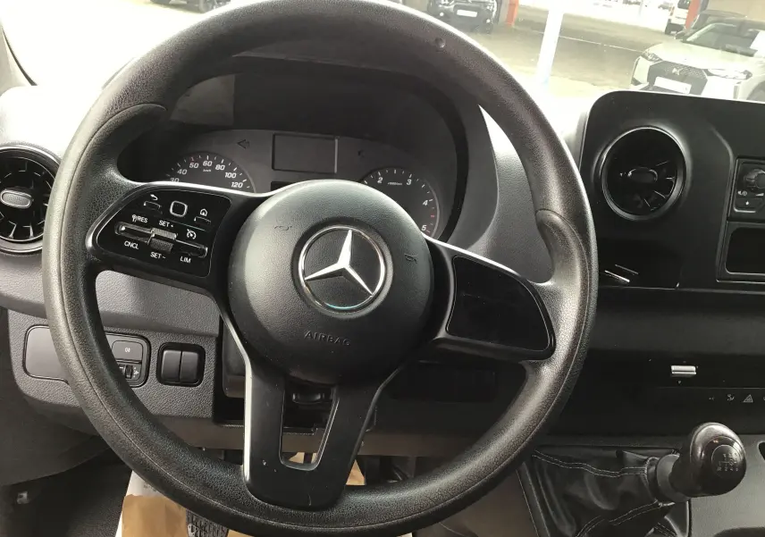 Vue rapprochée du volant noir Mercedes Sprinter 2018 avec commandes intégrées et levier de vitesses manuel visible.