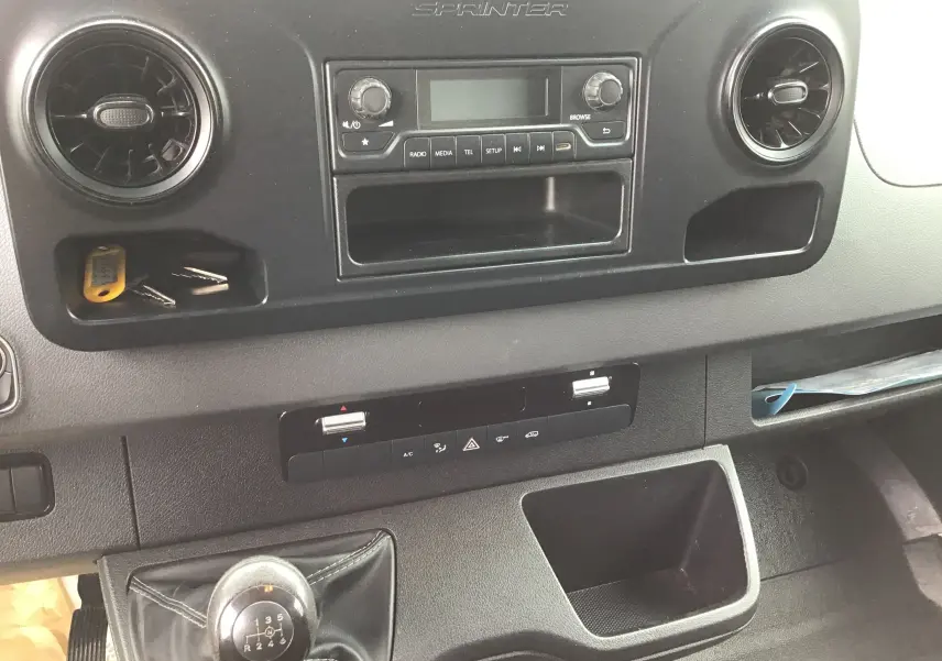 Vue rapprochée de la console centrale intérieure noire du Mercedes Sprinter blanc, avec levier de vitesses manuel visible.