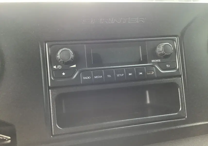 Vue rapprochée de la console centrale noire du Mercedes Sprinter 514 CDI avec commandes radio et inscription Sprinter.