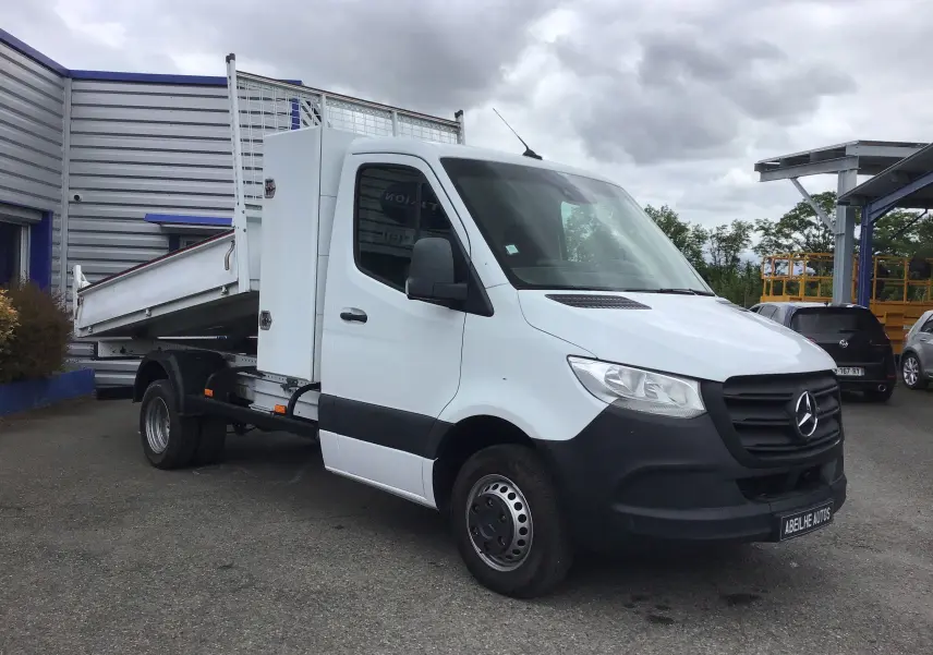 Vue 3/4 avant droite d'un Mercedes Sprinter blanc avec benne basculante et coffre latéral sur châssis cabine.