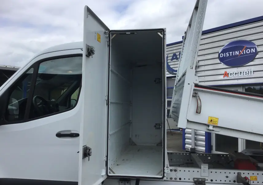Vue latérale gauche d'un Mercedes Sprinter blanc 2018 avec benne relevée et coffre ouvert montrant l'intérieur vide.