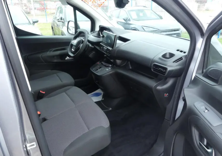 Intérieur avant droit du Peugeot Partner gris métallisé 2025, montrant sièges tissu et tableau de bord moderne.