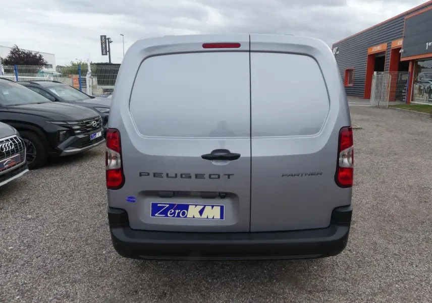 Vue arrière d'un Peugeot Partner gris métallisé 2025 avec portes battantes et plaque d'immatriculation ZeroKM visible.