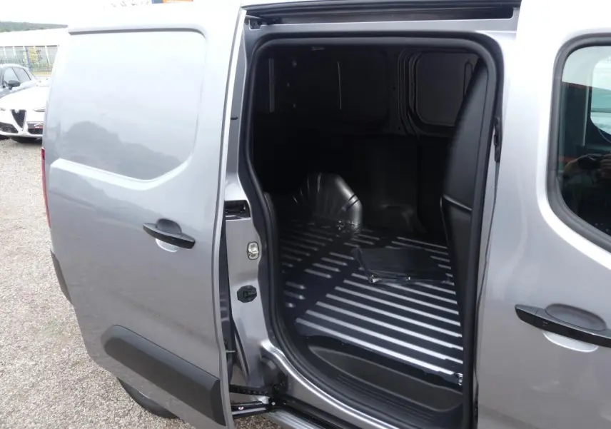 Vue côté droit du Peugeot Partner XL gris métallisé avec porte coulissante ouverte sur l'espace de chargement vide.