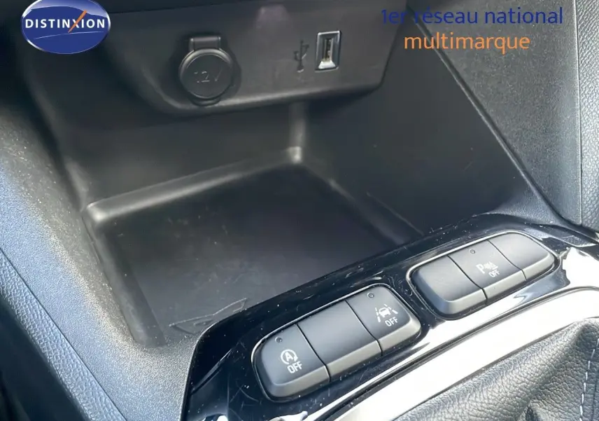 Vue rapprochée de la console centrale de l’Opel Corsa gris Kristall Metal montrant les boutons de contrôle et prise 12V.